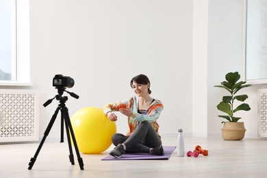 Happy sports blogger recording fitness lesson with camera at home