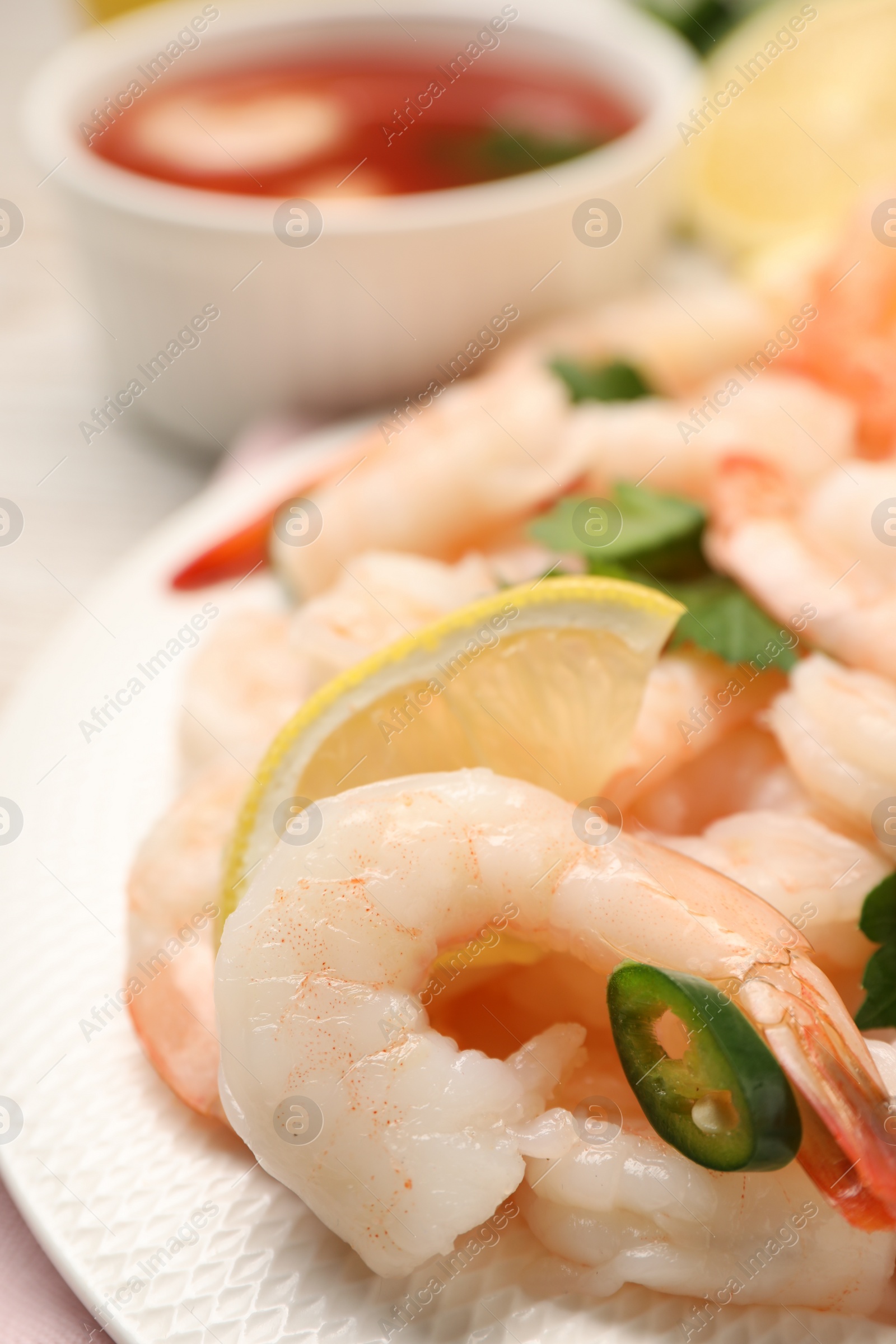 Photo of Tasty boiled shrimps with cocktail sauce, chili and parsley on table, closeup