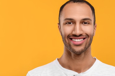 Photo of Portrait of smiling man with healthy clean teeth on orange background. Space for text