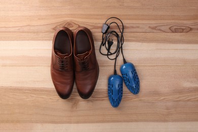 Photo of Shoes and electric dryer on wooden background, flat lay