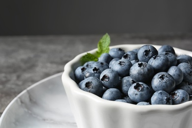 Photo of Crockery with juicy blueberries on color table, closeup