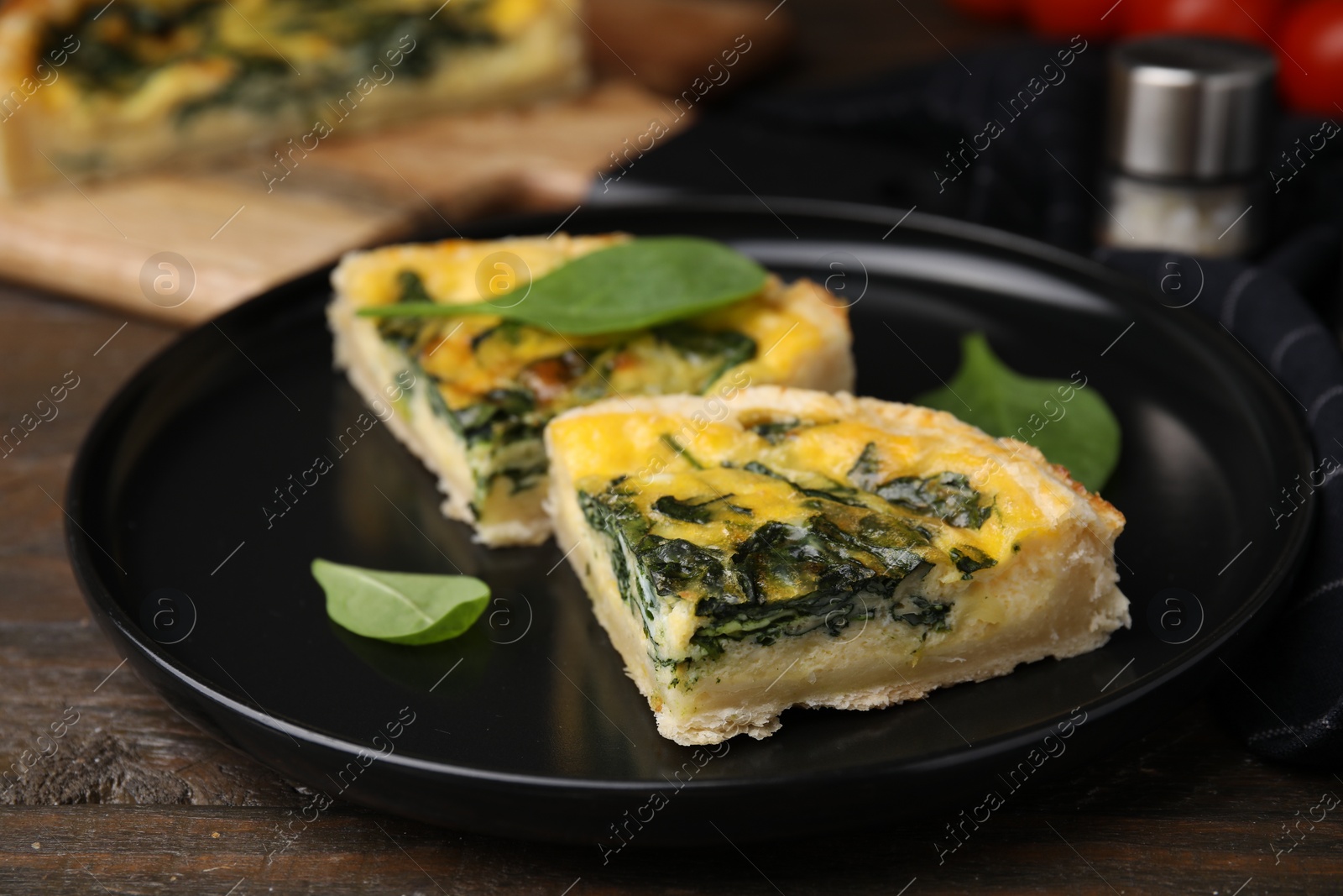 Photo of Pieces of delicious pie with spinach on wooden table, closeup