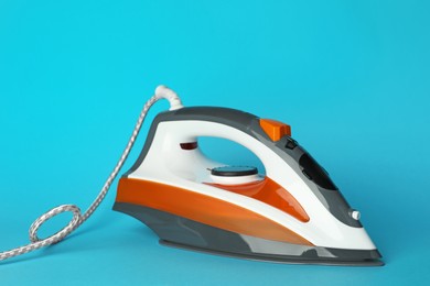 Photo of One modern iron on light blue background. Home appliance