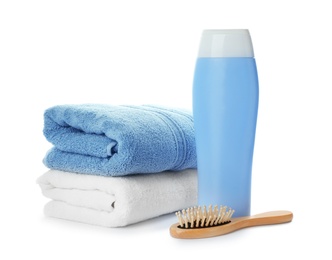 Photo of Folded towels, hair brush and shampoo isolated on white