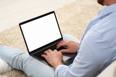 Photo of Man using laptop on floor indoors, closeup view