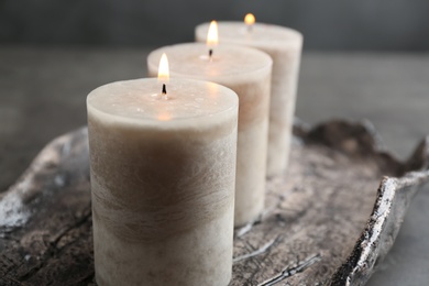 Tray with three burning candles on table