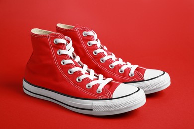 Photo of Pair of new stylish sneakers on red background