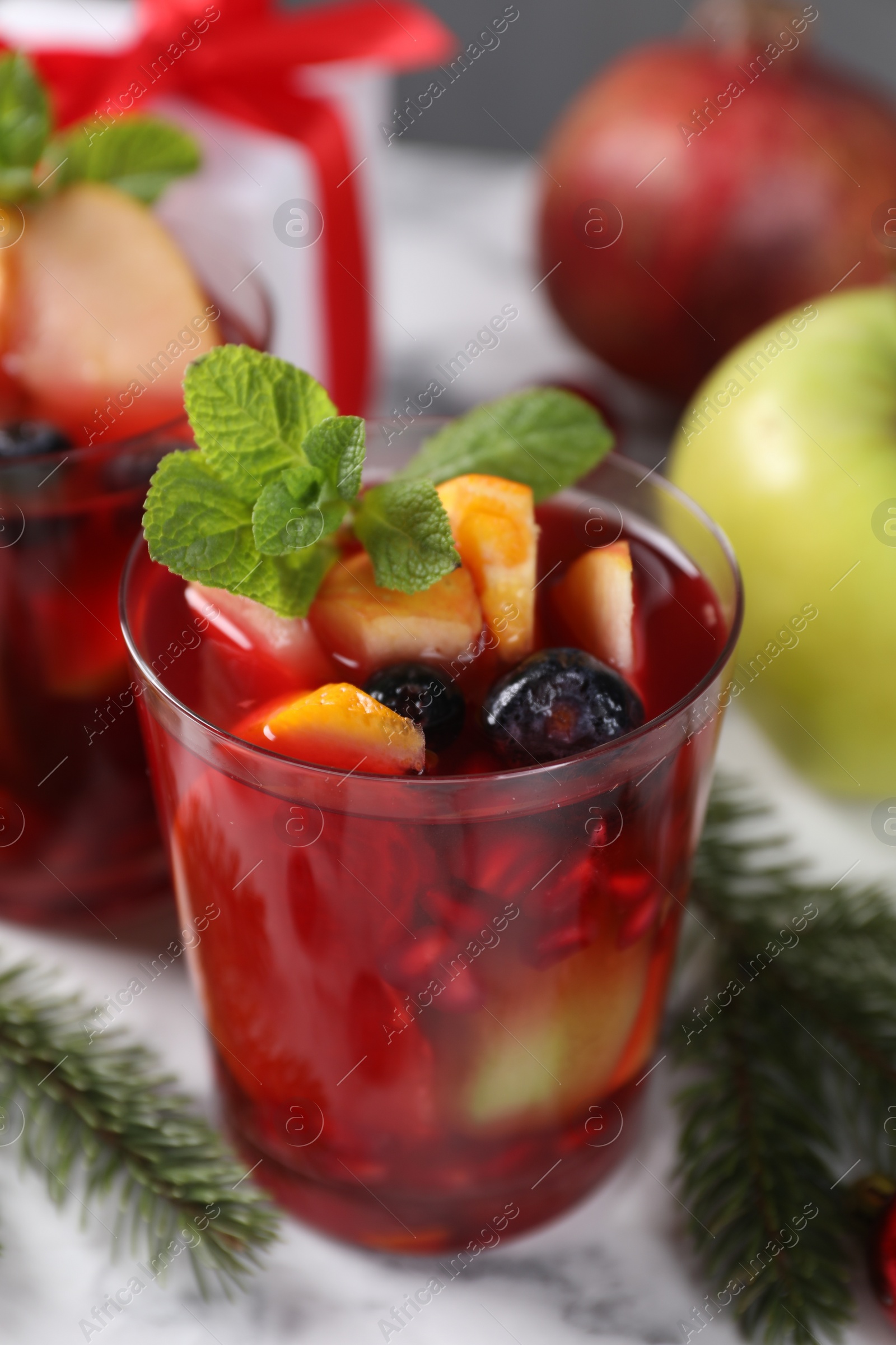 Photo of Aromatic Sangria drink in glasses, ingredients and Christmas decor on white marble table