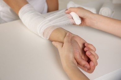 Doctor applying bandage onto patient's arm in hospital, closeup