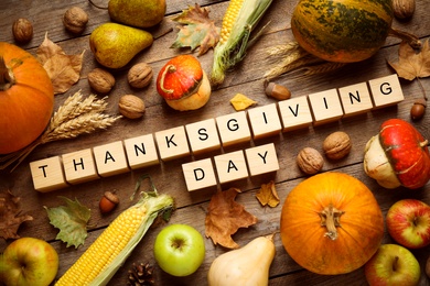 Cubes with phrase THANKSGIVING DAY, autumn fruits and vegetables on wooden background, flat lay. Happy holiday