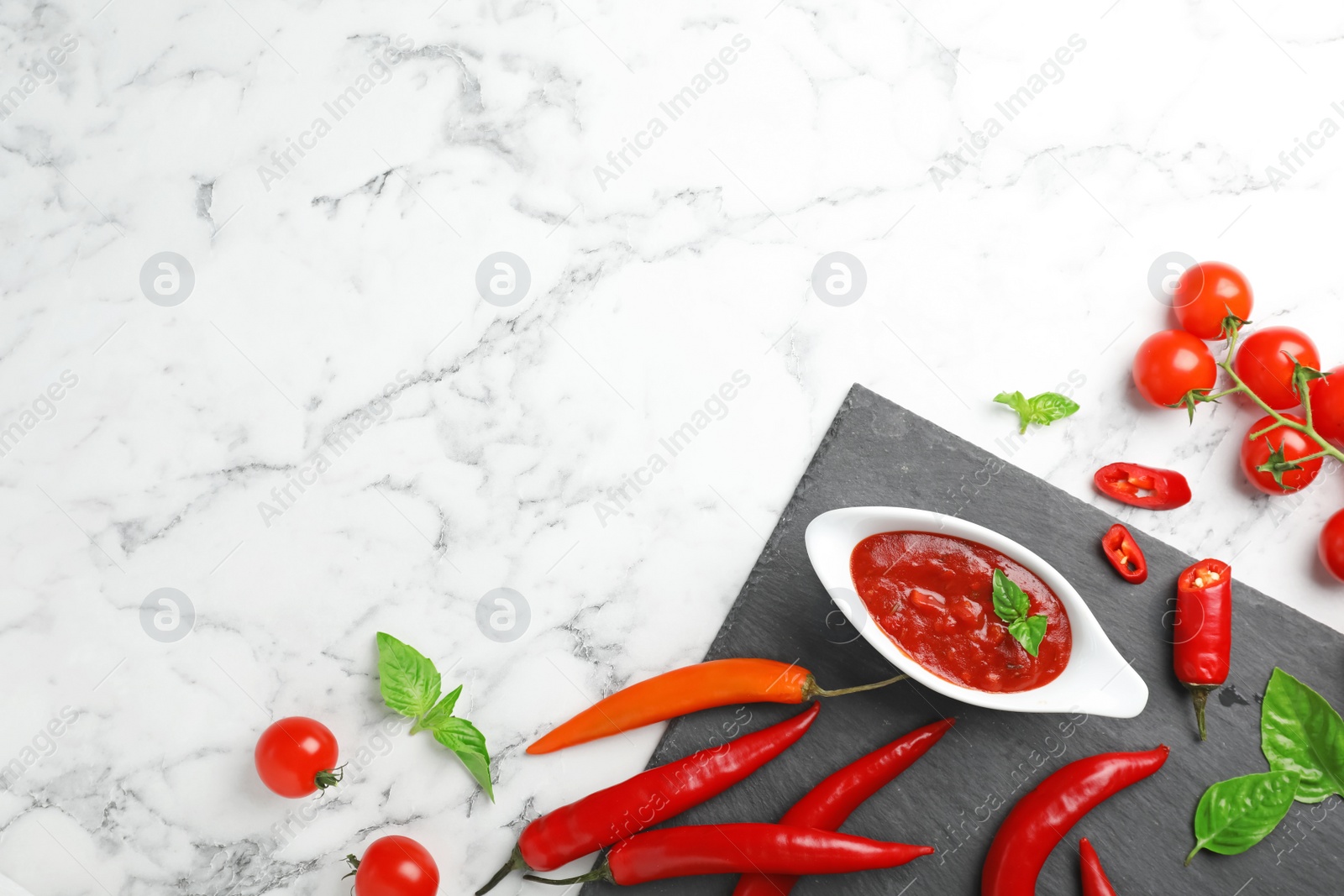 Photo of Flat lay composition with gravy boat of spicy chili sauce on marble background