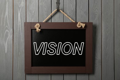 Image of Small chalkboard with word Vision hanging on grey wooden wall