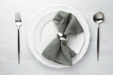 Photo of Stylish setting with cutlery, napkin and plates on light textured table, flat lay