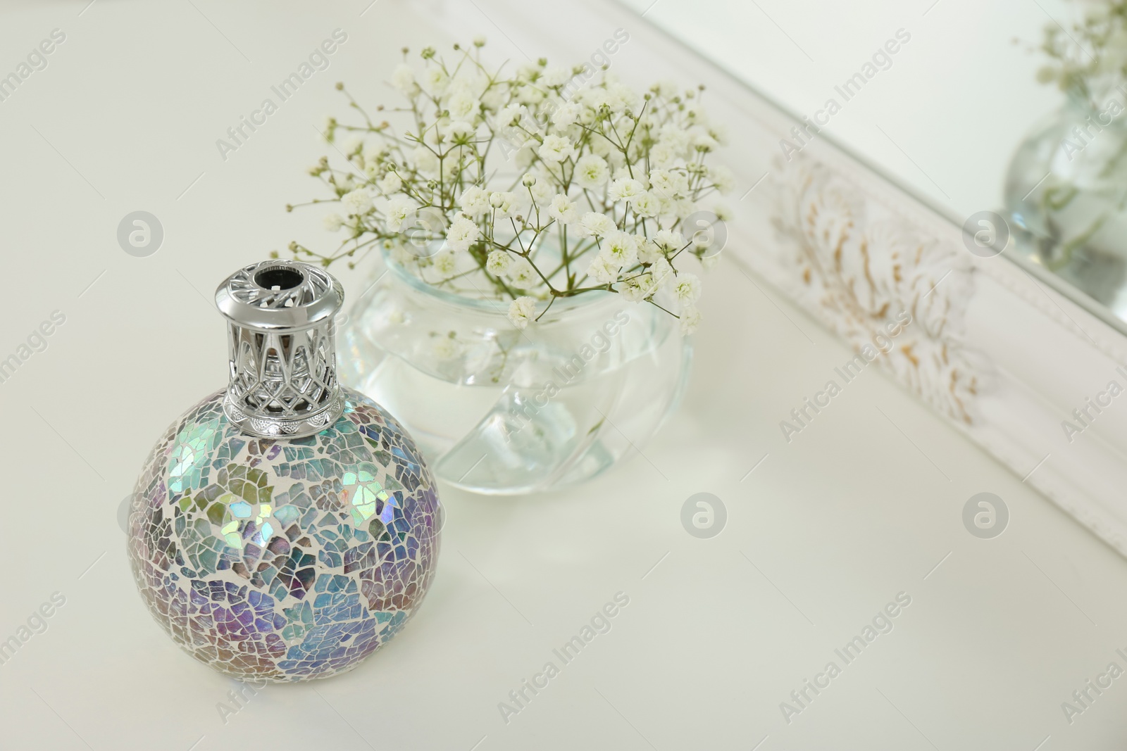 Photo of Stylish catalytic lamp with beautiful gypsophila on white table, space for text. Cozy interior