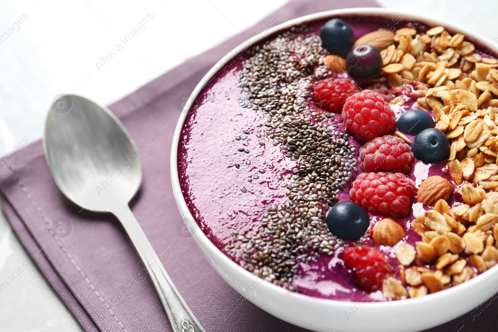 Photo of Delicious acai smoothie with granola and berries in bowl on table, closeup