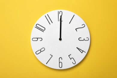 Photo of Modern clock on yellow background, top view