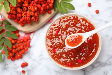 Photo of Flat lay composition with delicious rowan jam and berries on white marble table. Space for text