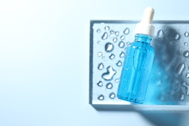 Bottle of cosmetic serum on light blue background, top view. Space for text