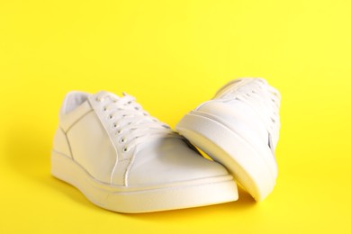 Photo of Pair of stylish white sneakers on yellow background