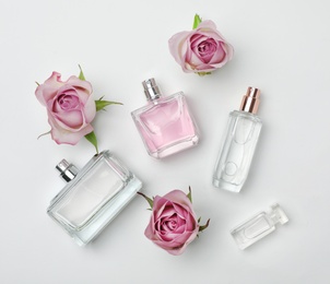 Photo of Composition with transparent bottles of perfume and beautiful flowers on white background