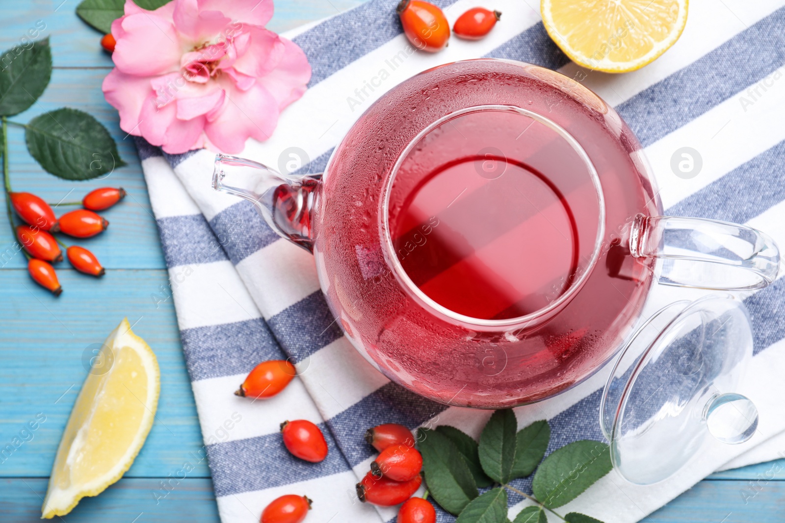 Photo of Fresh rose hip tea and berries on blue wooden table, flat lay