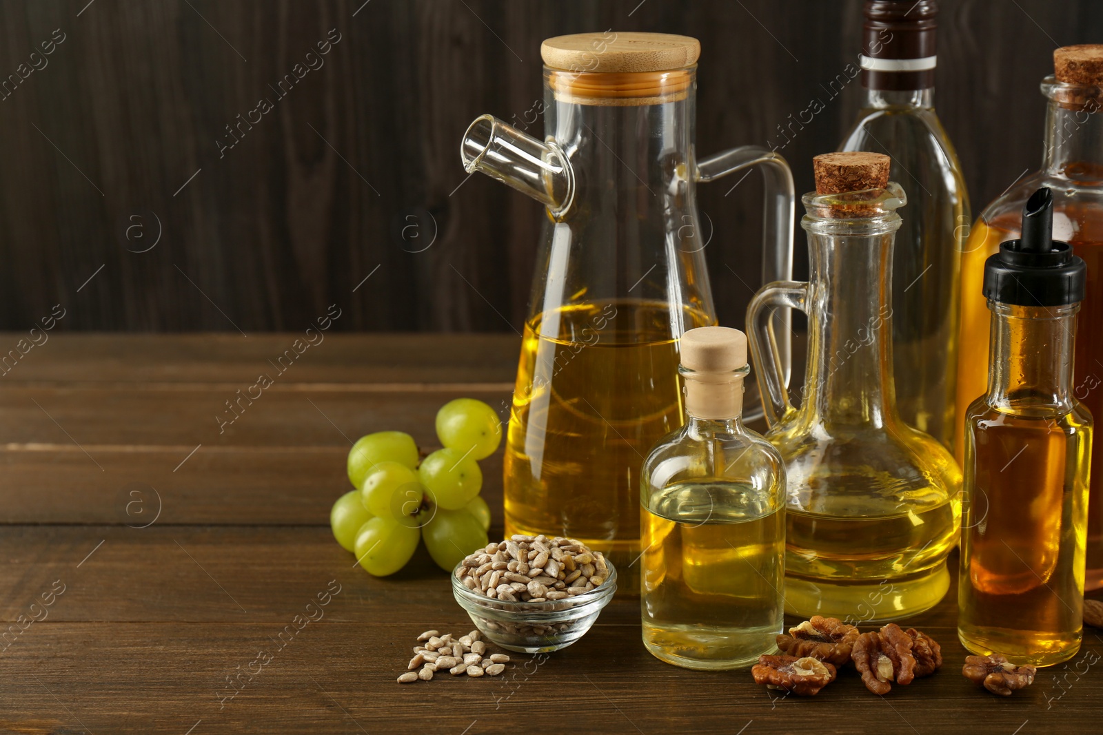 Photo of Vegetable fats. Different oils in glass bottles and ingredients on wooden table, space for text