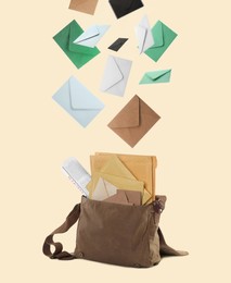 Many different envelopes falling into brown postman's bag on beige background