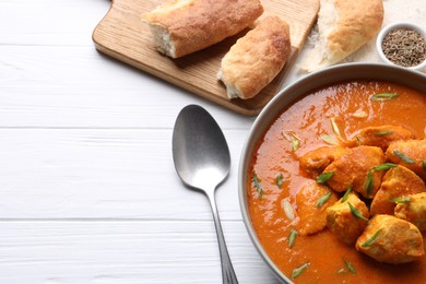 Photo of Bowl of delicious chicken curry on white wooden table, above view. Space for text