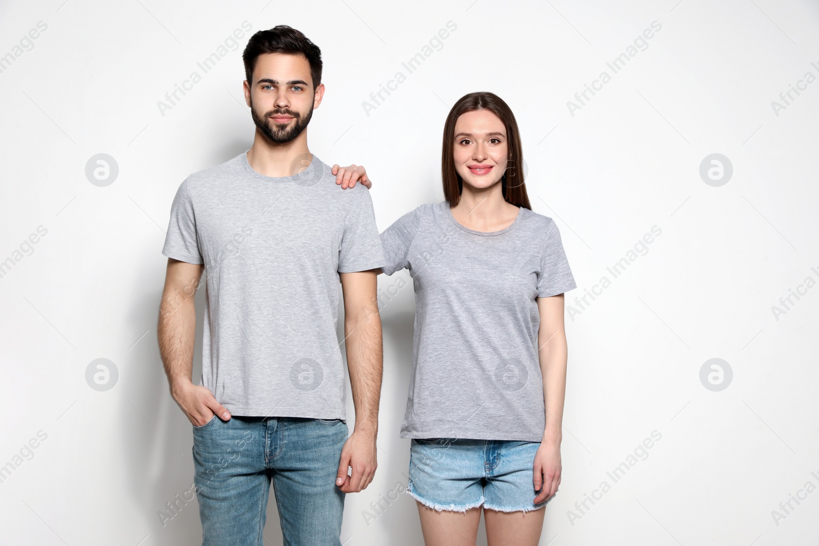 Photo of Young people in t-shirts on light background. Mock up for design