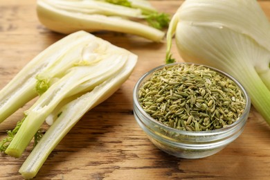 Photo of Fennel seeds in bowl and fresh vegetables on wooden table, closeup