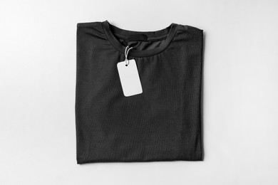 Photo of Stylish black T-shirt with label on white background, top view