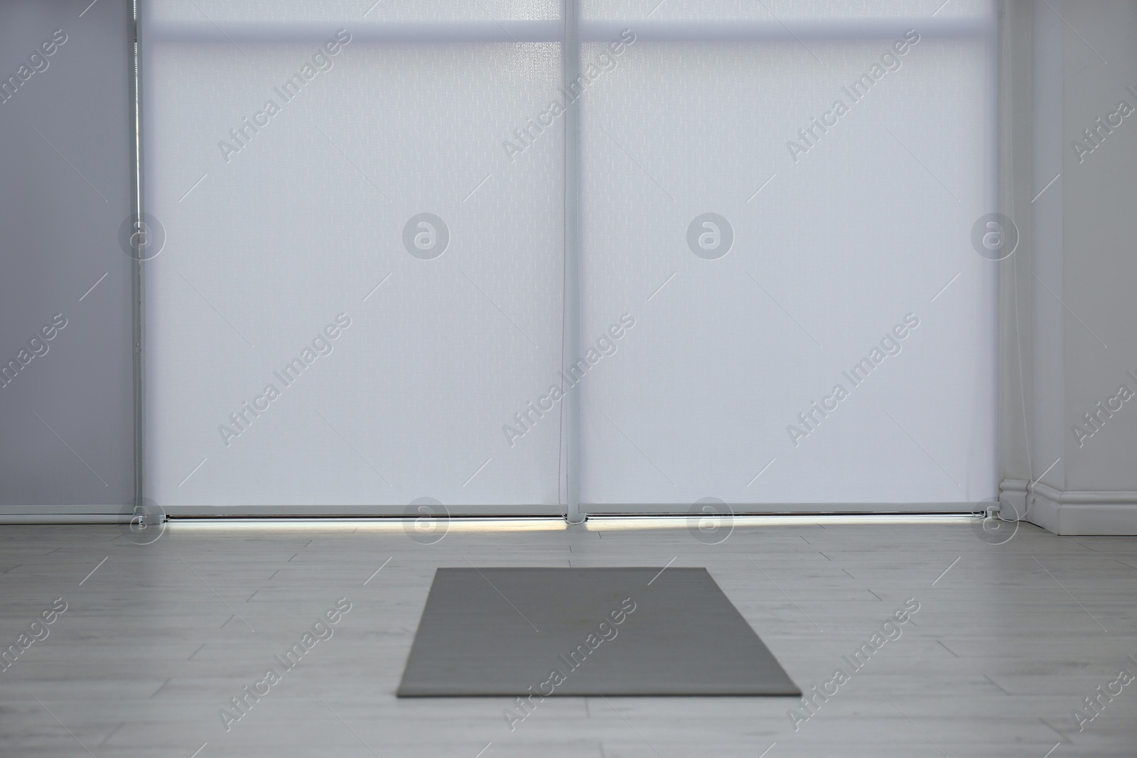 Photo of Unrolled grey yoga mat on floor in room