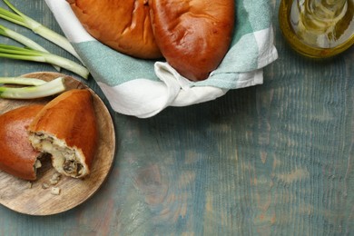 Delicious baked patties with meat and mushrooms on blue wooden table, flat lay. Space for text