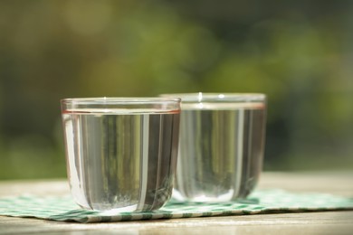 Photo of Glasses of pure water on wooden table, closeup