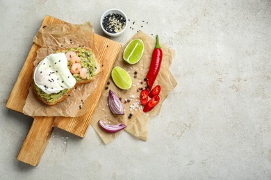 Delicious sandwich with guacamole, shrimps, fried egg and ingredients on light grey table, flat lay. Space for text