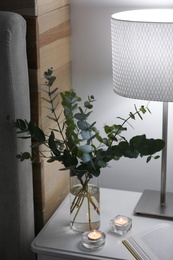 Photo of Beautiful eucalyptus branches on nightstand in bedroom. Interior design