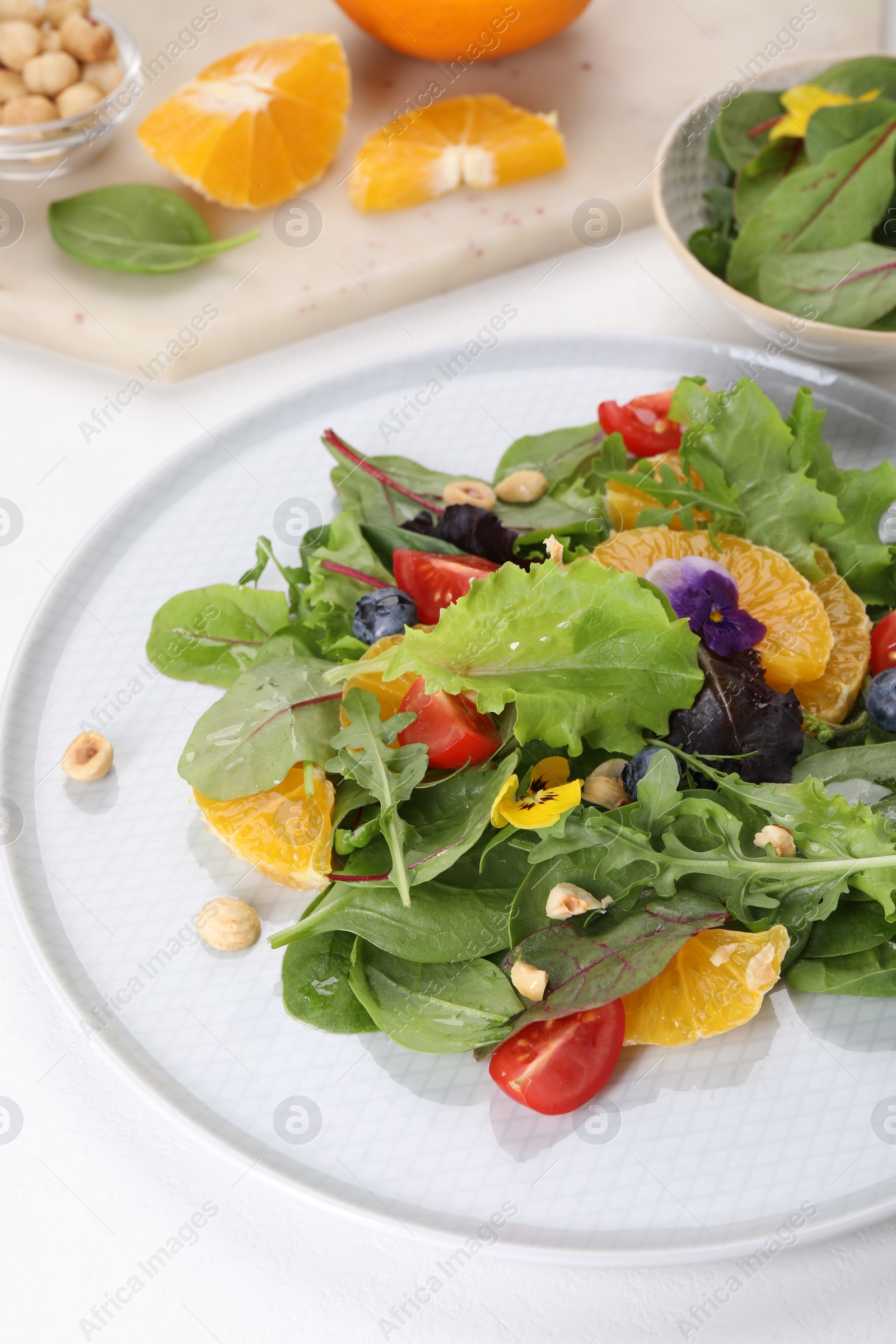 Photo of Delicious salad with tomatoes and orange slices on white table