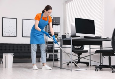 Photo of Cleaning service. Woman washing floor with mop in office