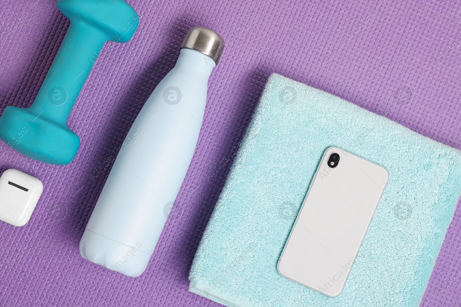 Photo of Flat lay composition with stylish thermo bottle and dumbbell on purple textured background