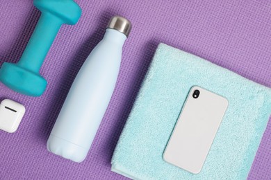 Photo of Flat lay composition with stylish thermo bottle and dumbbell on purple textured background