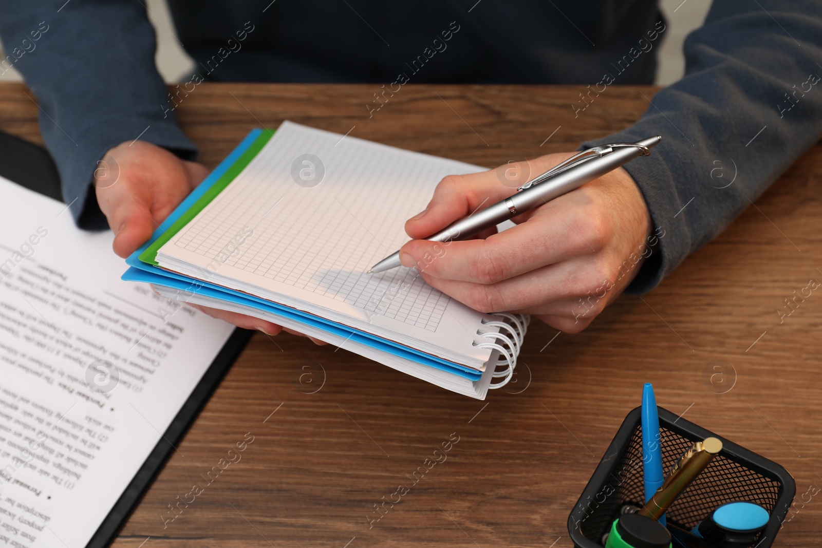 Photo of Man taking notes at wooden table, closeup