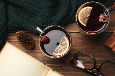 Photo of Glass cups of delicious mulled wine on wooden table, flat lay. Winter drink