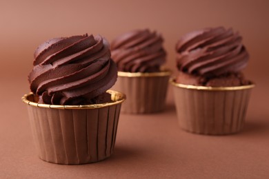 Delicious chocolate cupcakes on brown background, closeup