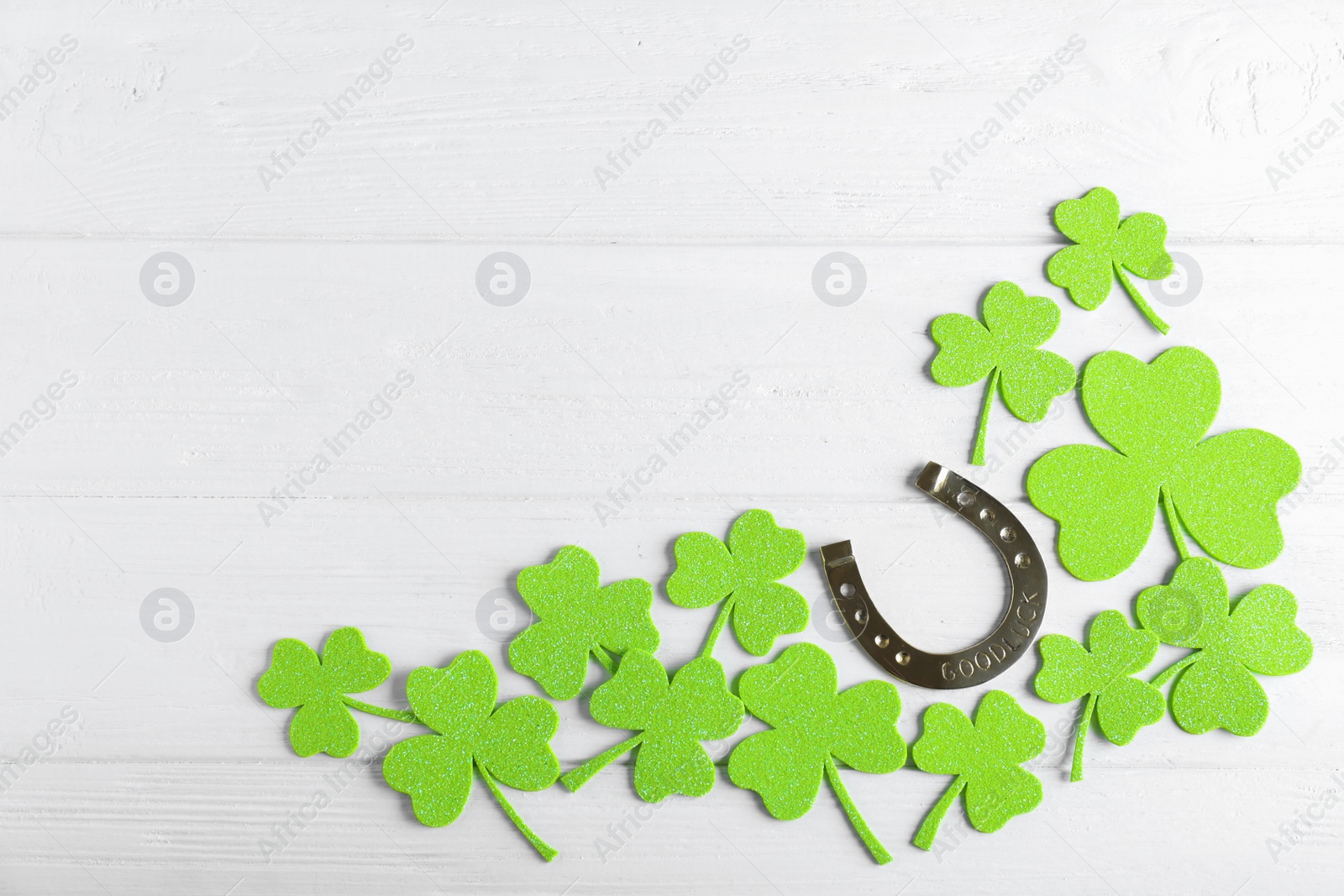 Photo of Flat lay composition with clover leaves on white wooden table, space for text. St. Patrick's Day celebration