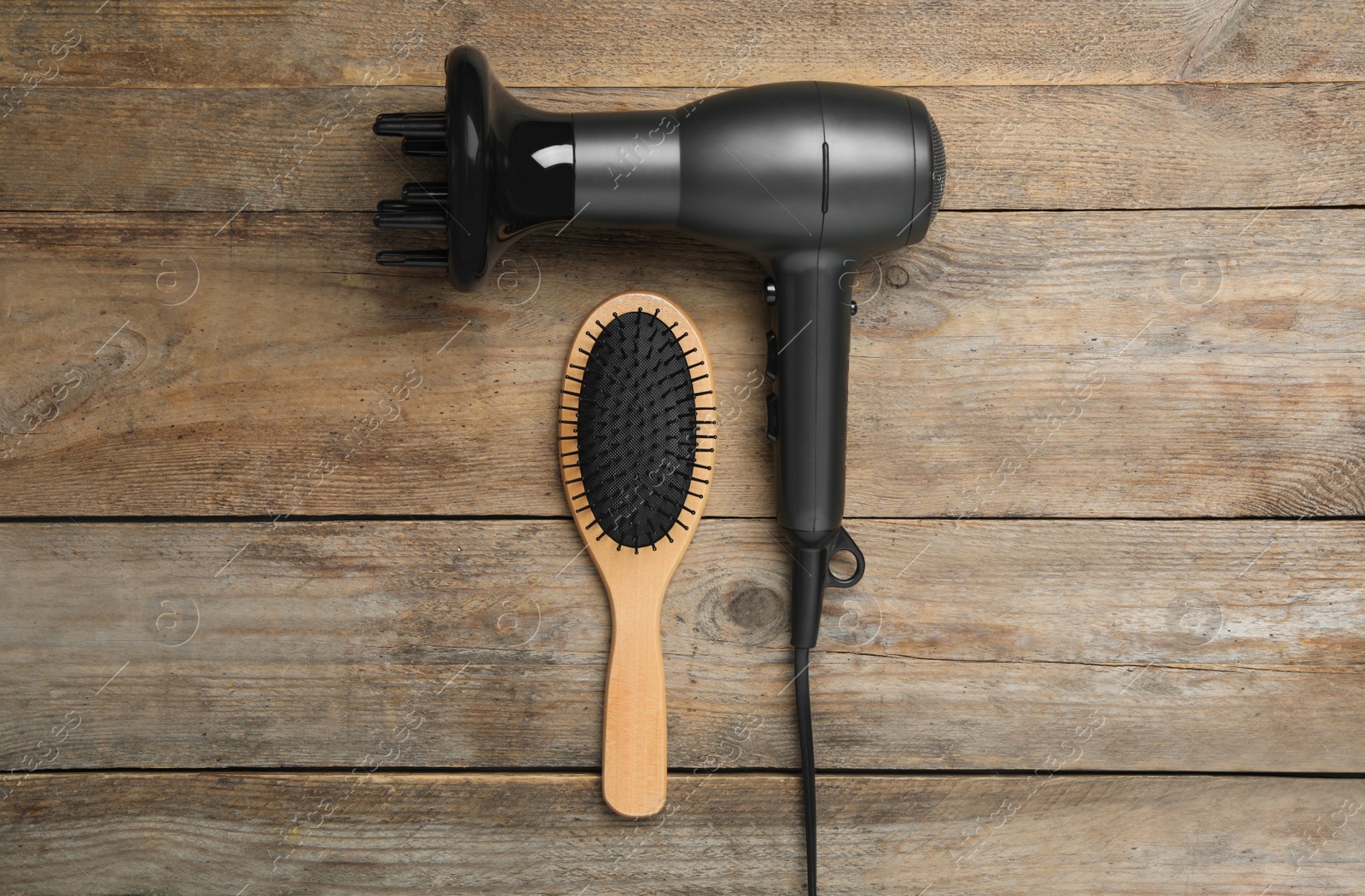 Photo of Hair dryer and brush on wooden table, flat lay. Professional hairdresser tool