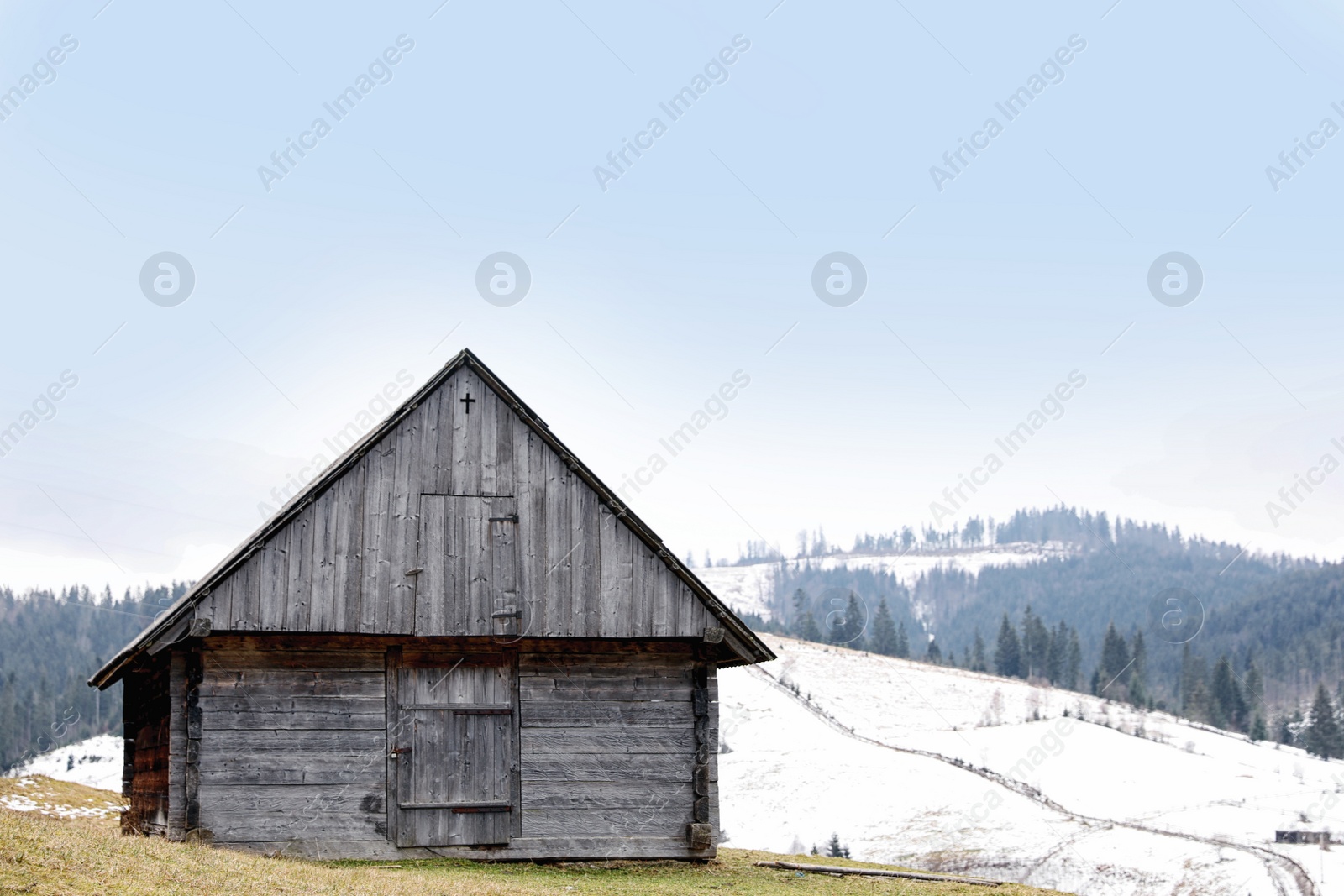 Photo of Beautiful winter landscape with wooden building and forest on snowy hill