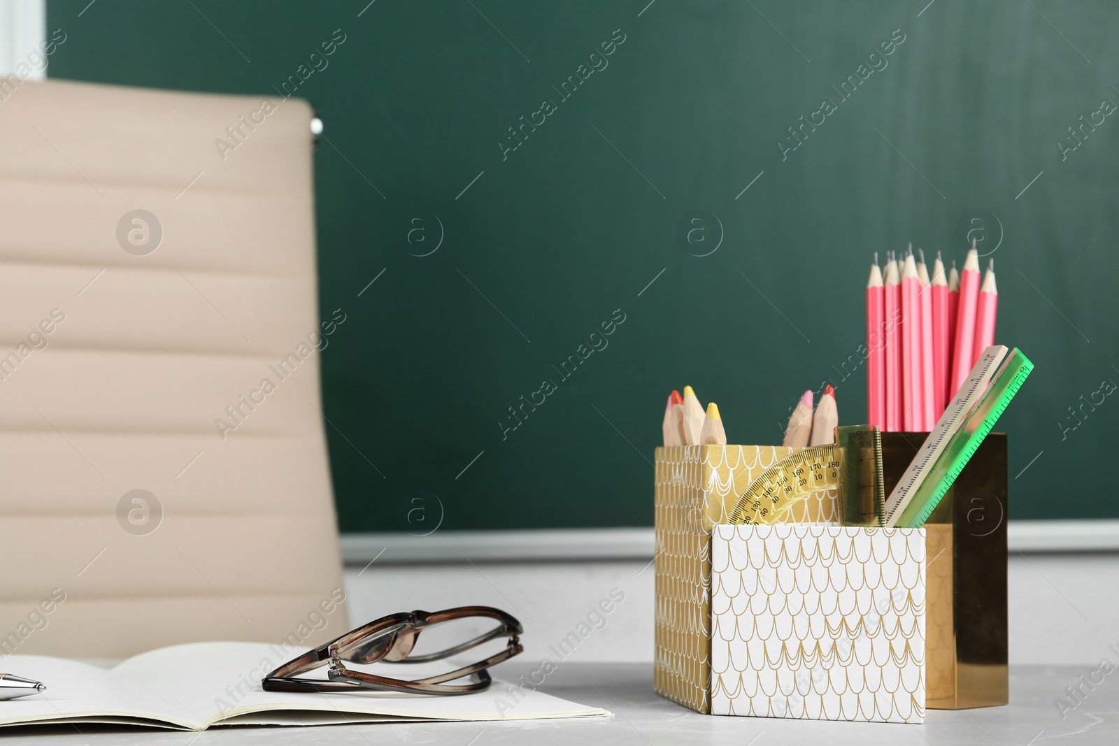 Photo of Stationery and eyeglasses on table near chalkboard in classroom. Happy teacher's day