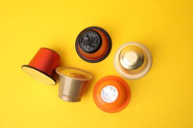 Photo of Many coffee capsules on yellow background, flat lay