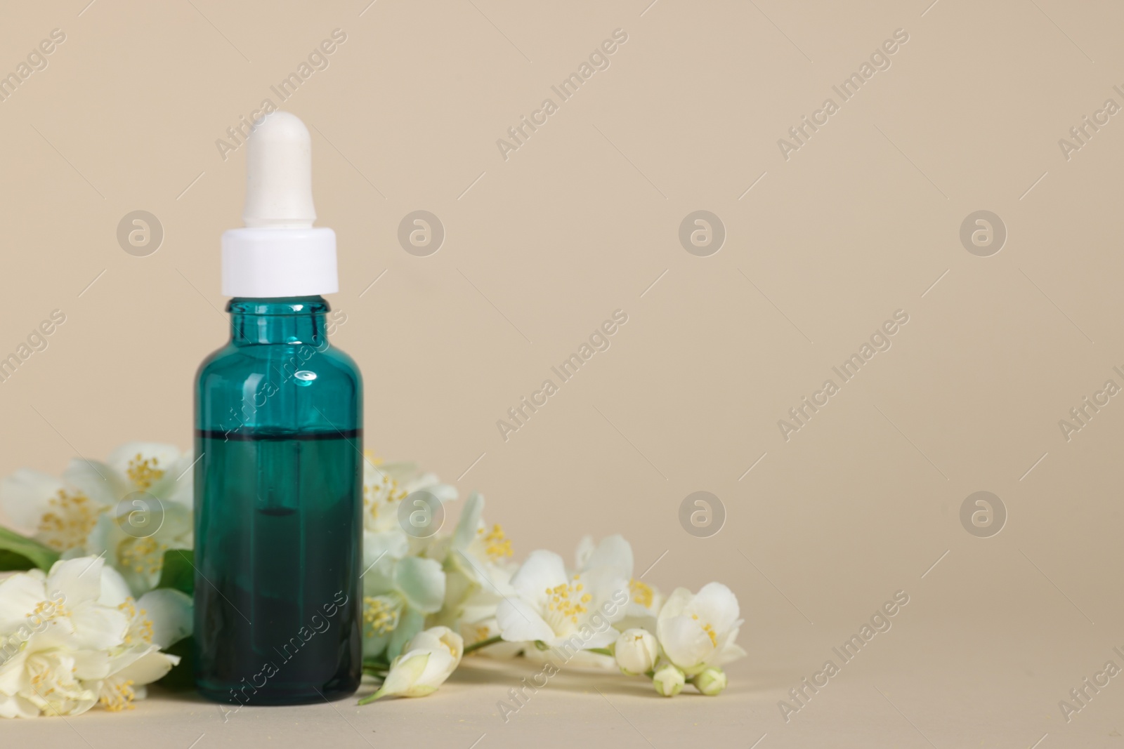 Photo of Essential oil in bottle and beautiful jasmine flowers on beige background, space for text