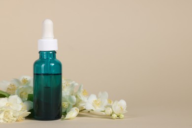 Photo of Essential oil in bottle and beautiful jasmine flowers on beige background, space for text